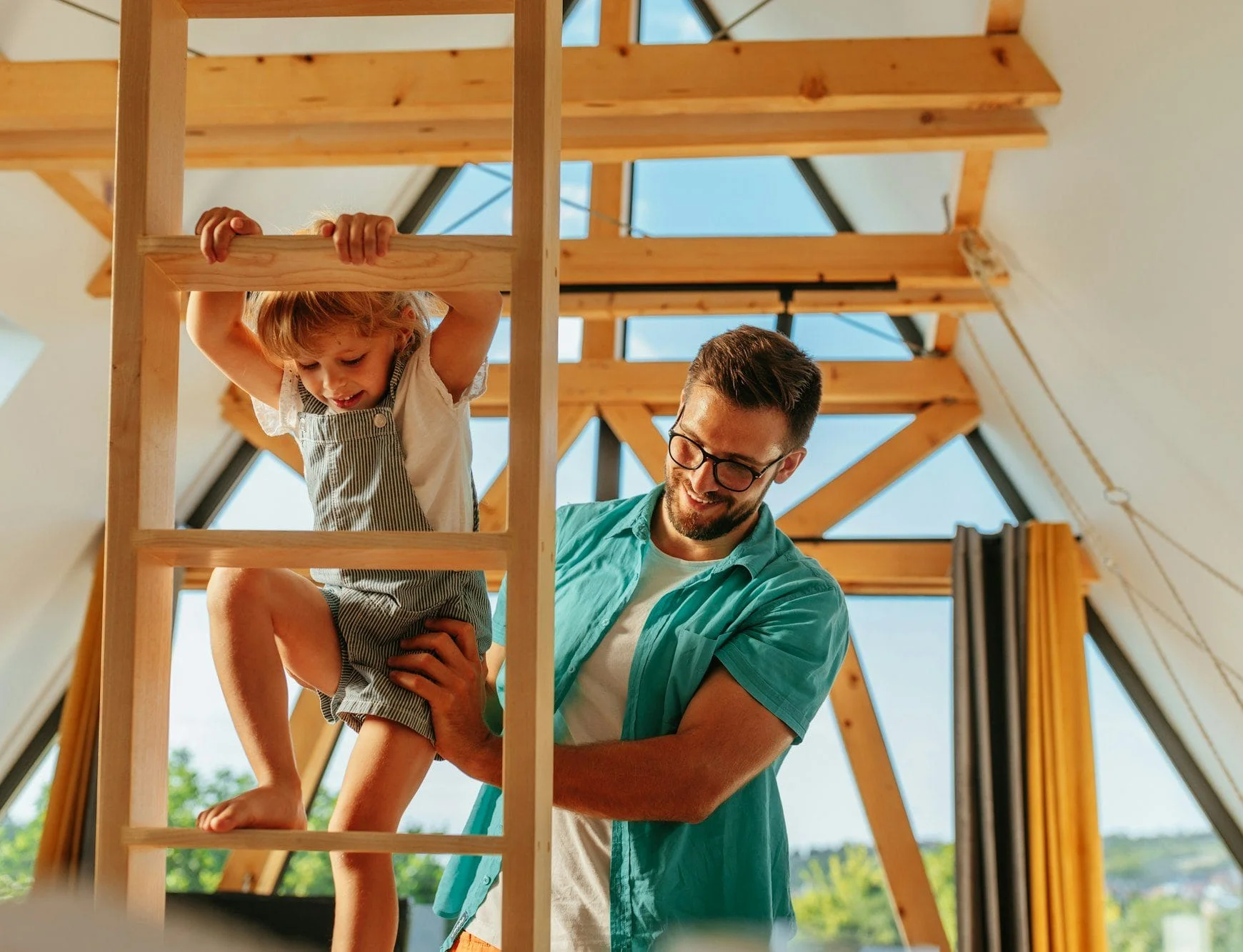 Girl climbing ladder with the help of her father