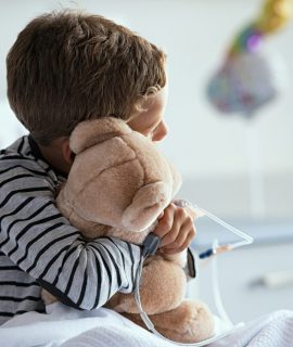 Child hugging teddy bear at hospital