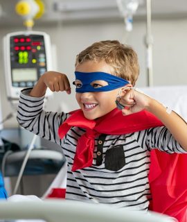 Strong boy in superhero costume at hospital